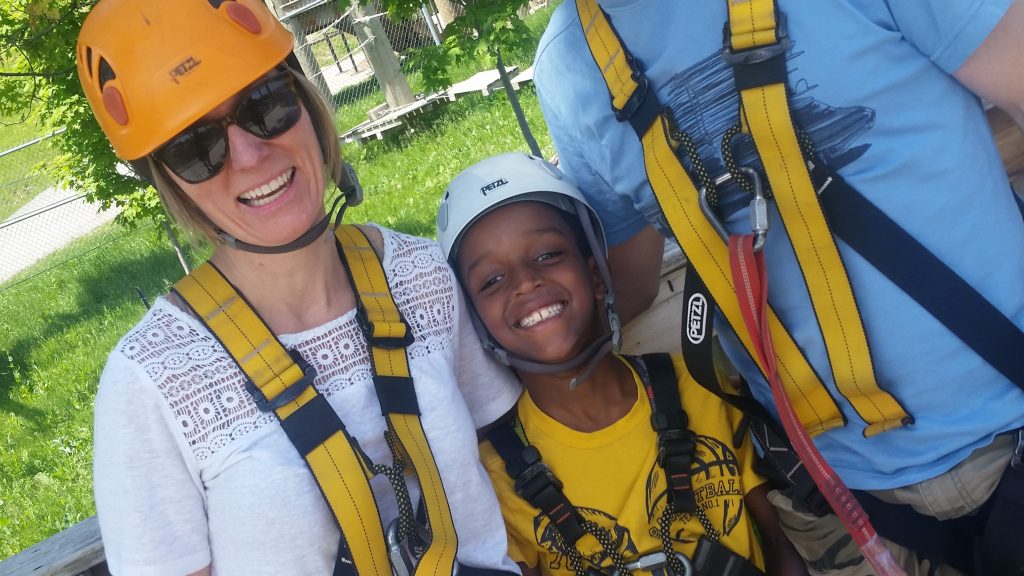 Image shows 2 adults and one child wearing harnesses and smiling.